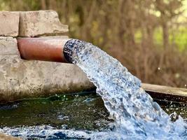 Bewässerungswasserfluss von Rohr zu Kanal für landwirtschaftliche Felder foto