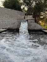 Bewässerungswasserfluss von Rohr zu Kanal für landwirtschaftliche Felder foto