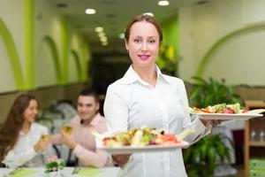 Kellnerin serviert den Besuchern Essen