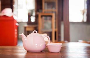 Teekanne und Tasse auf einem Holztisch foto