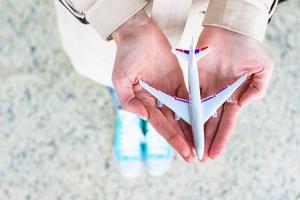 Nahaufnahmehand, die ein Flugzeugmodell am Flughafen hält foto