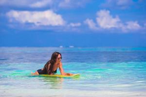 junges schlankes Surfmädchen am weißen Strand mit gelbem Surfbrett foto