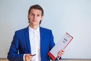 junger geschäftsmann mit geschäftsplan und finanzdokumenten in seinem büro foto