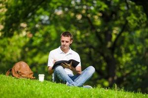 universitätsstudent, der draußen im park für prüfungen lernt. mit ihm seine Bücher, Notizbuch, Rucksack und Kaffee. foto