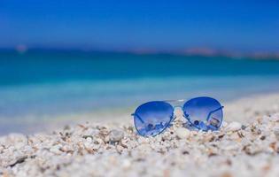 Nahaufnahme von bunten blauen Sonnenbrillen am tropischen Strand foto