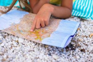 entzückendes kleines Mädchen mit Karte der Insel am tropischen Strand foto