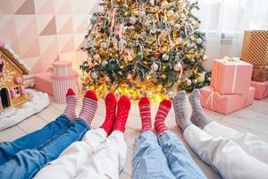 Nahaufnahme von Familienfüßen in Wollsocken am Weihnachtsbaum foto