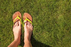 Nahaufnahme der Beine der Frau in Pantoffeln auf grünem Gras foto