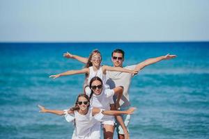 Glückliche Familie mit zwei Kindern hat Spaß am Strand foto