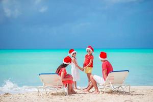 glückliche vierköpfige Familie am Strand in roten Weihnachtsmützen foto