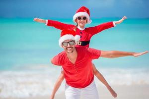 vater und tochter in weihnachtsmütze haben spaß am tropischen strand foto