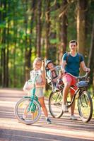 glückliche Familie, die draußen im Park radelt foto