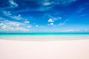 idyllischer tropischer strand in der karibik mit weißem sand, türkisfarbenem ozeanwasser und blauem himmel foto