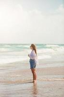 junge glückliche Frau am Strand genießt ihren Sommerurlaub. Mädchen ist glücklich und ruhig in ihrem Aufenthalt am Strand foto