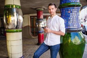 mann tourist mit stadtplan und rucksack in der europastraße. kaukasischer junge, der mit karte der europäischen stadt schaut. foto