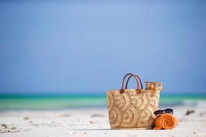 Strandzubehör - Spielzeugflugzeug, Strohsack, orangefarbenes Handtuch und Sonnenbrille am Strand foto