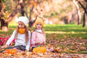 Kleine entzückende Mädchen mit Kürbis im Freien an einem warmen Herbsttag. foto