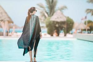 Frau, die sich am Pool in einem Luxushotelresort entspannt und einen perfekten Strandurlaub genießt foto