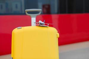 Nahaufnahme rote Pässe und kleines Flugzeugmodell auf gelbem Gepäck am Bahnhof foto