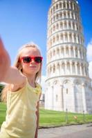 kleines mädchen, das selfie nimmt hintergrund der schiefe turm in pisa, italien foto