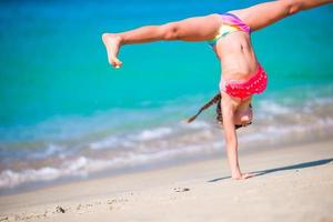 Entzückendes aktives kleines Mädchen am Strand während der Sommerferien foto