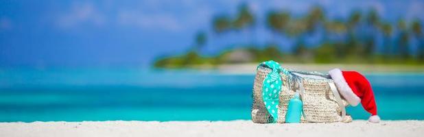 Strandzubehör mit Weihnachtsmütze am weißen tropischen Strand foto