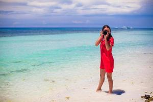 junge Frau fotografiert schöne Meereslandschaft am weißen Sandstrand foto