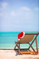 weihnachten am strand - stuhl mit weihnachtsmützen auf meer. Weihnachtsferienkonzept foto