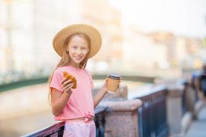 Frau mit Croissant und Kaffee im Freien auf der Promenade foto