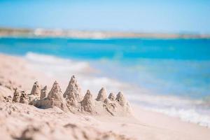 Sandburg am weißen tropischen Strand mit Plastikspielzeug für Kinder foto