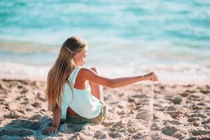 entzückendes kleines Mädchen am Strand während der Sommerferien foto