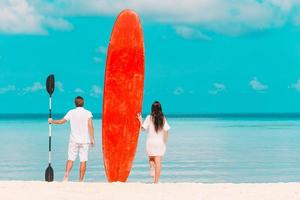 junges paar mit rotem surfbrett während des tropischen urlaubs foto