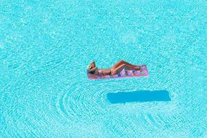 junge Frau im Bikini Luftmatratze im großen Swimmingpool foto