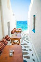 Bänke mit Kissen in einem typisch griechischen Café im Freien auf Mykonos mit herrlichem Meerblick auf die Kykladeninseln foto