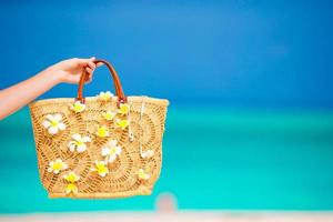 Closeup schöne Tasche mit Frangipani-Blüten im Hintergrund das Meer foto