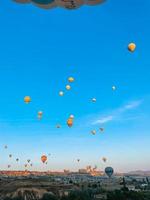 Heißluftballon fliegt über felsige Landschaften in Kappadokien mit schönem Himmel im Hintergrund foto