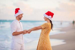 glückliches paar in weihnachtsmützen auf weihnachtsstrandurlaub foto