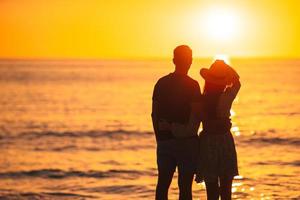 romantisches Paar am Strand bei farbenprächtigem Sonnenuntergang im Hintergrund foto
