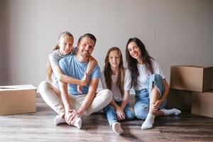 Glückliche Familie mit zwei Töchtern mit Kartons im neuen Haus am Umzugstag foto