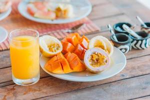 Leckere exotische Früchte - reife Passionsfrucht, Mango zum Frühstück im Restaurant im Freien foto