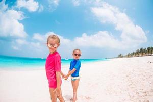 kleine glückliche lustige mädchen haben viel spaß am tropischen strand, der zusammen spielt. foto