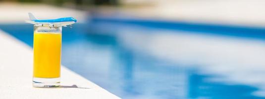 sommer- und reisekonzept kleines flugzeugmodell und glas orangensaft in der nähe des pools foto