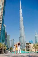 glückliche familie, die in dubai mit wolkenkratzern im hintergrund geht. foto