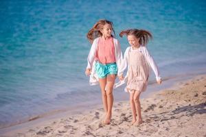 kleine glückliche lustige mädchen haben viel spaß am tropischen strand, der zusammen spielt. foto