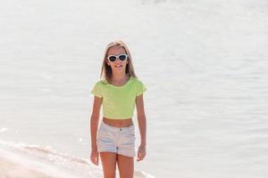 Entzückendes aktives kleines Mädchen am Strand während der Sommerferien foto