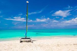 Katamaran mit buntem Segel am karibischen Strand foto