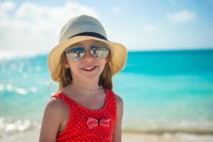 glückliches kleines Mädchen mit Hut am Strand während der Sommerferien foto