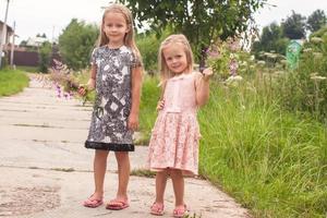 Kleine entzückende Mädchen, die mit Blumen im Freien spazieren gehen foto