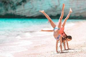 Entzückende kleine Mädchen haben gemeinsam Spaß am weißen tropischen Strand foto