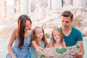 glückliche familie in der nähe von fontana di trevi mit stadtplan foto